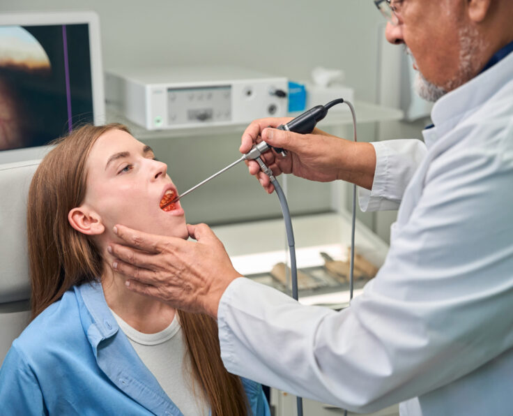 Medical professional carefully examines the patients throat using a specialized medical tool in a clinic setting